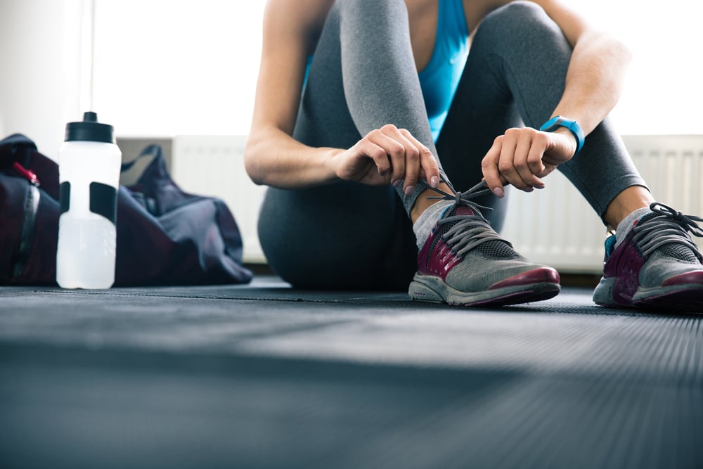 Woman tying shoelaces at gym Woman tying shoelaces at gym